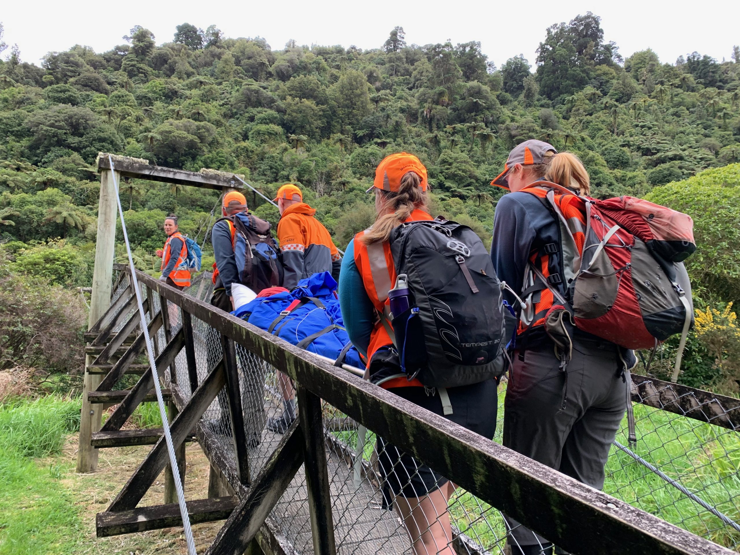 Team of Wellington LandSAR members carrying a patient over a bridge in a stretcher